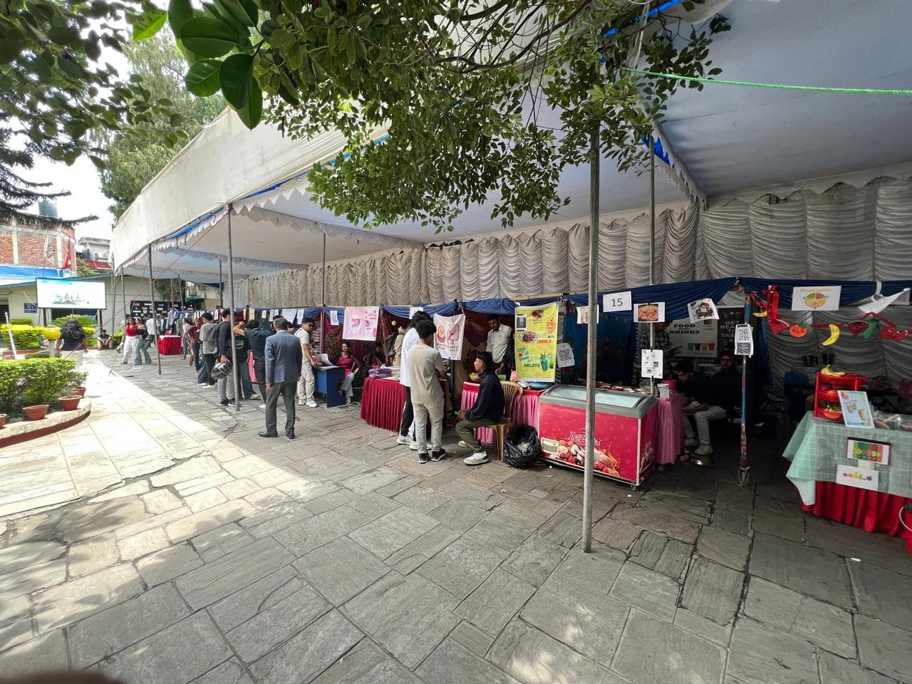 Visitors interact with various startup stalls under a large canopy at the Uniglobe IT expo and Startup mela 2025.
