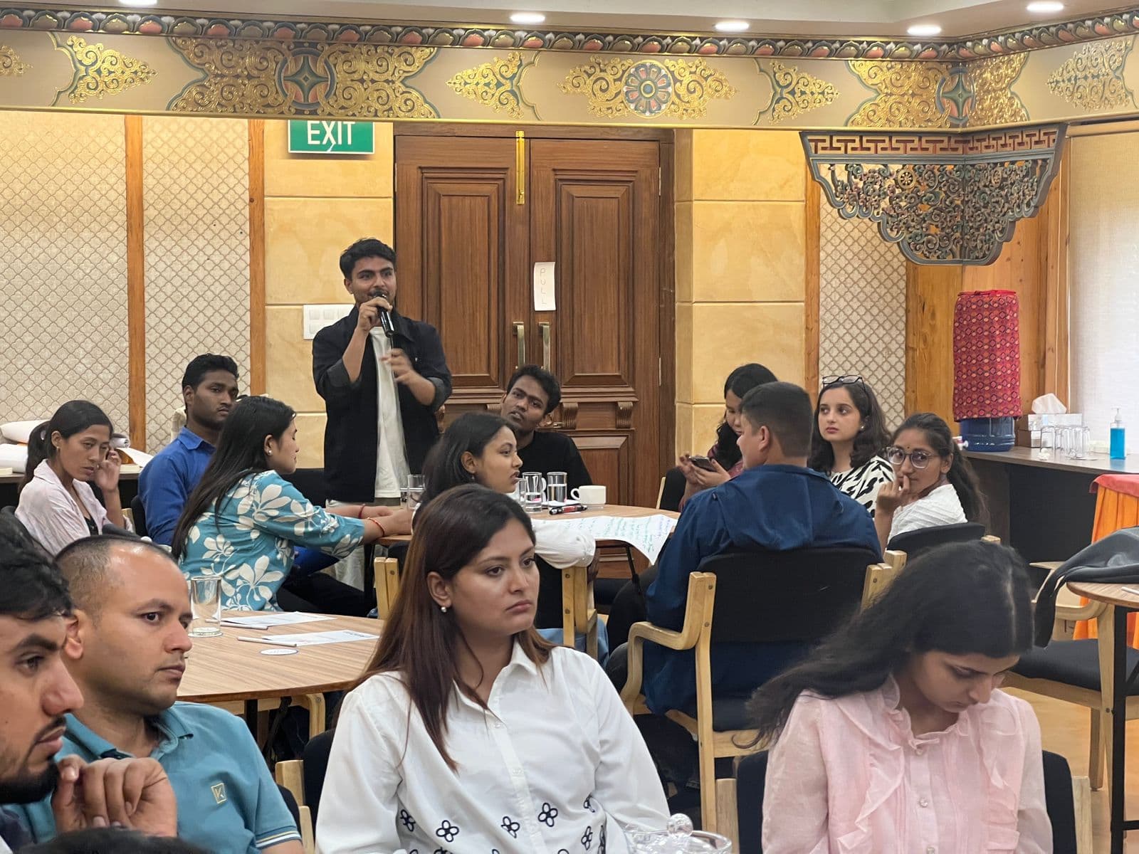 A participant speaks into a microphone during a group discussion at the Ipas Nepal workshop on Climate Change, Gender, and SRHR, surrounded by attentive attendees.