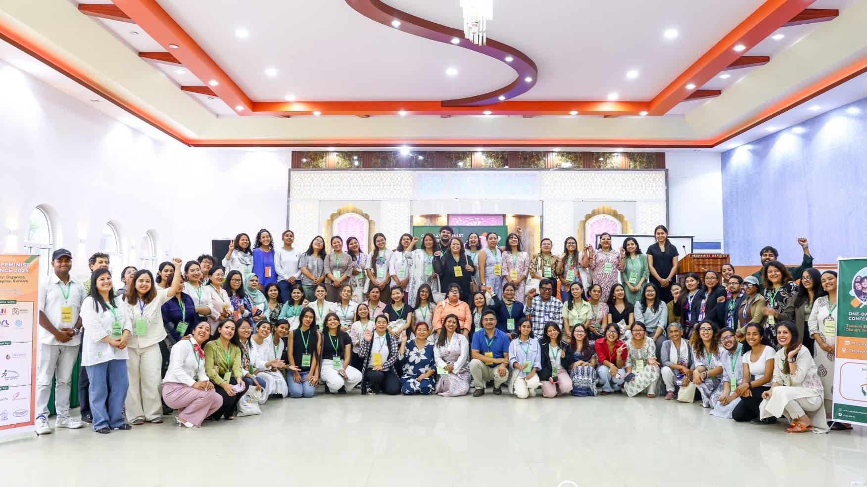 A large group of diverse attendees poses for a group photo at the "One-day Feminist Conference 2025."